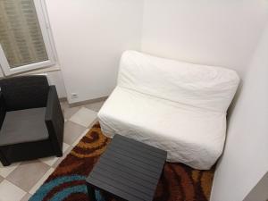 Cama blanca en habitación con silla en L'orléanaise hébergements cosy, en Orléans