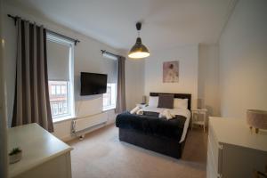Schlafzimmer mit einem Bett und einem Flachbild-TV in der Unterkunft Insurance Stays - Anfield L4 - Spacious house in Liverpool