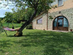una hamaca atada a un árbol delante de una casa en La Piccola fattoria en Todi