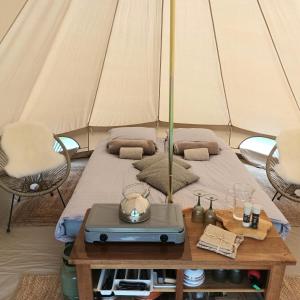 Zelt mit einem Bett und einem Tisch in der Unterkunft De Langenbrinck Eerlijk Heerlijk overnachten in blokhut en ingerichte tent in Breedenbroek