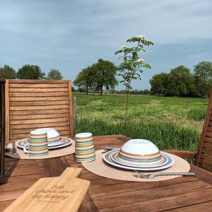 een houten tafel met borden en hoeden op een veld bij De Langenbrinck Eerlijk Heerlijk overnachten in blokhut en ingerichte tent in Breedenbroek