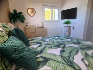 een slaapkamer met een bed met een deken met bladeren bij Petit coin de paradis les pieds dans l’eau in La Londe-les-Maures