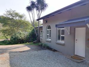 a white house with a driveway and a palm tree at Shingalana Cottages in White River