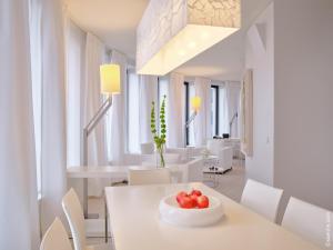 a white dining room with a bowl of fruit on a table at Dorint Kurfürstendamm Berlin in Berlin