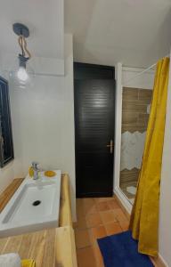 uma casa de banho com um lavatório e um chuveiro em Lever du soleil em La Trinité