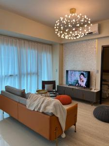 a living room with a couch and a flat screen tv at Luxurious 1 Br Facing Manila Bay Sunset Nearby Okada MOA Solaire Ayala Malls in Manila