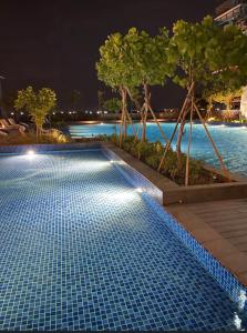 a swimming pool at night with trees and water at Luxurious 1 Br Facing Manila Bay Sunset Nearby Okada MOA Solaire Ayala Malls in Manila