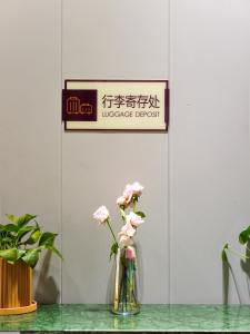 um vaso com flores cor-de-rosa sentado numa mesa em Rose International Hotel em Xangai