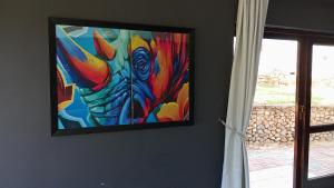 a painting hanging on a wall with a window at Kloof in Pretoria