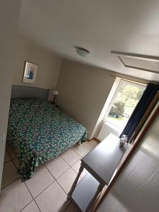 um quarto com uma cama, uma mesa e uma janela em Les Pieds dans l'eau, Gîte Le Blagour em Lachapelle-Auzac