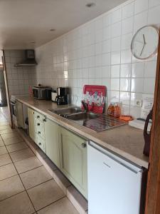 um balcão de cozinha com um lavatório e um relógio na parede em Les Pieds dans l'eau, Gîte Le Blagour em Lachapelle-Auzac