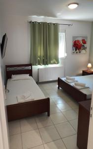 sypialnia z 2 łóżkami i oknem z zielonymi zasłonami w obiekcie KANALI HOLIDAYS APARTMENT 1 w Kanalionie