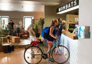a woman with a bike standing at a counter in a store at Wombat's City Hostel Vienna Naschmarkt in Vienna
