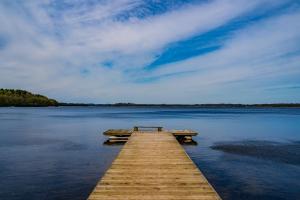 un molo di legno su un lago con una panchina sopra di POCZUJ NATURĘ - domki nad jeziorem a Stare Wierzchowo