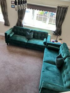 a living room with a green couch and a window at Ida House in Ormesby