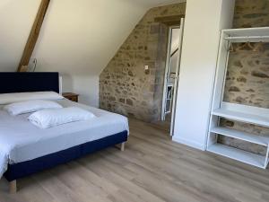 1 dormitorio con cama y pared de piedra en Erquy Les Hirondelles, en Erquy