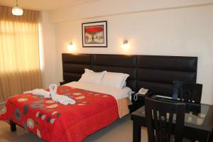 um quarto de hotel com uma cama com um cobertor vermelho em Hotel Reggia em Tacna