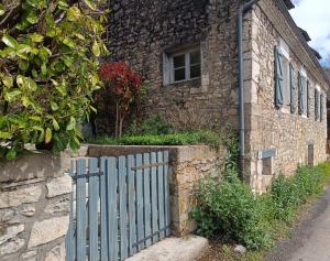 uma cerca azul em frente a uma casa de pedra em Les Pieds dans l'eau, Gîte Le Blagour em Lachapelle-Auzac