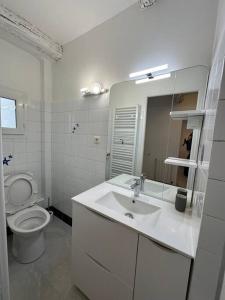 biała łazienka z umywalką i toaletą w obiekcie L'idéal à Nîmes w mieście Nîmes