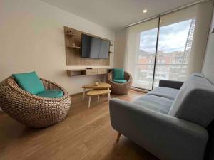 uma sala de estar com um sofá e cadeiras e uma televisão em Hermoso Apartamento de 2 habitaciones en Usaquen em Bogotá