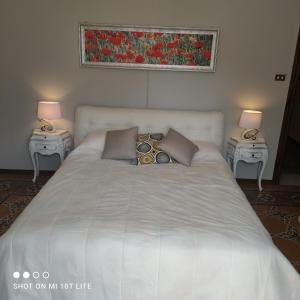 a large white bed with two night tables with lamps at tita's house in Lucca