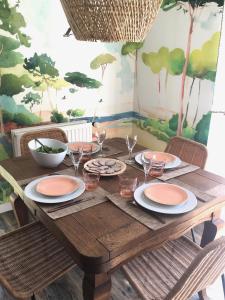 a wooden table with plates and wine glasses on it at Maison lumineuse entre terre et mer in Séné
