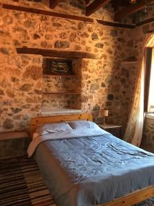 a bedroom with a bed in a stone wall at Fani's house in Kastanítsa