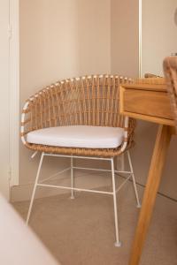 a rattan chair sitting next to a wooden table at Hôtel BO & MIA in La Baule