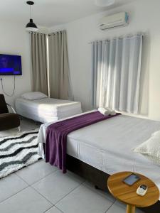 sypialnia z 2 łóżkami, stołem i telewizorem w obiekcie SUITE ELEGACY w mieście Serra de São Bento