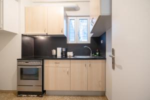 eine Küche mit Holzschränken, einer Spüle und einem Herd in der Unterkunft Katehaki metro station 2 persons apartment by MPS in Athen