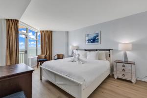 a bedroom with a large white bed and a desk at Carolinian Resort 2032 in Myrtle Beach