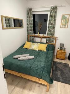 ムロンゴヴォにあるBezdroża Mazurskieのベッド(緑のシーツ、黄色の枕付)