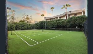 a tennis court in front of a building with palm trees at Ocean View-breath Taking Views, Amazing Facilities in Perth