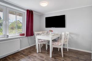 a white dining room with a white table and chairs at Reetferienhaus Lütt in Schaprode