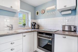 a kitchen with white cabinets and a sink at Reetferienhaus Lütt in Schaprode