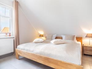 um quarto com uma grande cama branca e 2 almofadas em Haus STRANDLUST WF-05 em Wustrow