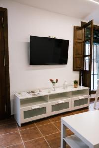 un centro de entretenimiento blanco con TV de pantalla plana en la pared en Casa Ochavada, en Archidona