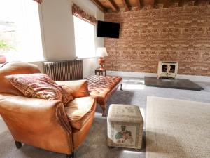 a living room with leather furniture and a brick wall at The Old Barn in Market Rasen