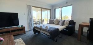 a living room with a couch and a flat screen tv at Sandcastles Beachfront Luxury Retreat Apartment in Perth