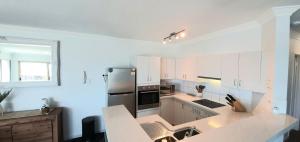 a kitchen with white cabinets and a stainless steel refrigerator at Sandcastles Beachfront Luxury Retreat Apartment in Perth