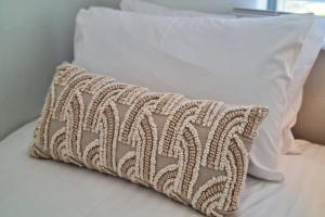 uma almofada sentada em cima de uma cama branca em Scarborough Beach Front Resort - Shell Ten em Perth