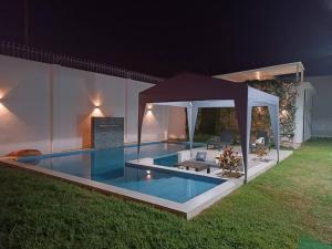 uma piscina com um gazebo num quintal à noite em Casa de campo Jumbo em Laredo Hacienda