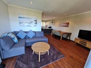 - un salon avec un canapé bleu et une table dans l'établissement Summer Breeze - Holiday Or Business Apartment, à Perth