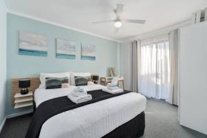 a bedroom with a large bed with towels on it at Chic 2 Bed Apartment On Scarborough Beach in Perth
