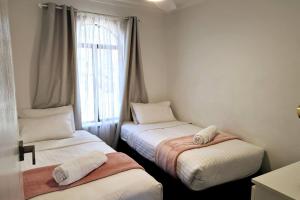 Chic 2 Bed Apartment On Scarborough Beach في بيرث: سريرين توأم في غرفة مع نافذة