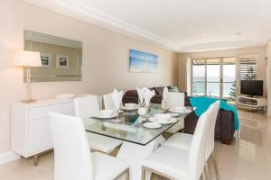 a dining room with a glass table and white chairs at The White Pearl Penthouse in Perth