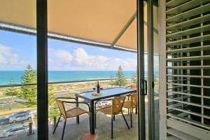 a table and chairs on a balcony with a view of the ocean at The White Pearl Penthouse in Perth