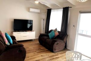 a living room with two chairs and a flat screen tv at West Beach Lagoon 123 - Location & Views!!! in Perth