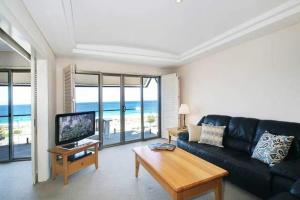 ein Wohnzimmer mit einem schwarzen Sofa und einem TV in der Unterkunft The Sea Breeze Penthouse Apartment in Perth
