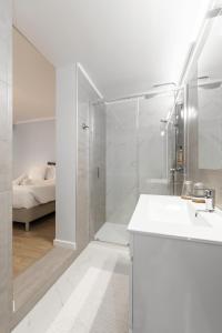 a white bathroom with a shower and a sink at Fika Guest House in Nazaré